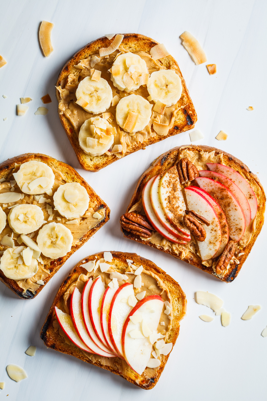 Peanut butter toasts with banana and apple on a gray background, flat lay.